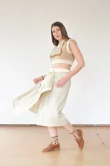 Falda midi color beige de corte evasé, con estructura envolvente y caída fluida. Se ajusta con broches a presión metálicos y cinturón de la misma tela.