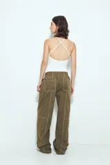 Pantalón tipo babucha de tiro bajo, color verde oliva, con silueta amplia y costuras visibles en contraste blanco. Posee cintura elástica con lazo blanco para ajuste.