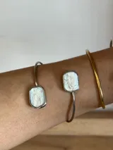 Brazalete abierto dorado de bronce con extremos decorados con perlas de río irregulares.