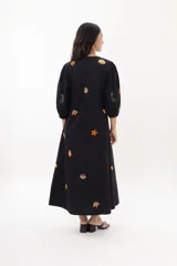 Vestido largo blanco de algodón con bordados de motivos marinos en tonos naranja, verde y azul. Tiene escote en V, mangas 3/4 abullonadas y cierre frontal con botones.