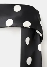 Vestido largo negro con estampado de lunares blancos, diseño asimétrico de un solo hombro y tejido fluido de poliéster. Incluye un fular a juego para el cuello.