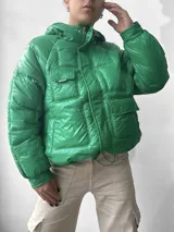 Campera puffer verde con capucha, cierre frontal con cremallera y bolsillos con solapa.