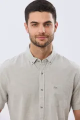 Camisa de manga corta confeccionada en mezcla de lino y algodón, con estampado de cuadros pequeños en tonos azules. Presenta cuello camisero con botones, cierre frontal abotonado, bolsillo aplicado en el pecho y dobladillo redondeado.