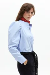 Camisa celeste de popelina 100% algodón, con cuello mao, hombros abullonados y mangas largas. Cierre frontal con botones de nácar.