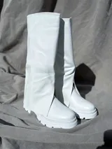 Bota de caña alta color blanco, con suela track y abertura lateral.