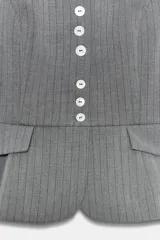 Top entallado de cuello mao y manga corta abullonada, confeccionado en tejido con estampado de raya diplomática. Presenta cierre frontal con botones y detalle de solapas en la parte inferior delantera.