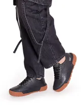Championes Cat modelo Amp para mujer, de color negro con textura punteada, cordones negros y suela de goma marrón con plataforma acanalada.