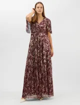 Vestido largo de fiesta con diseño cruzado, escote en V y drapeado lateral en la cintura. Presenta mangas cortas acampanadas y falda amplia con caída fluida. Confeccionado en tejido liviano con acabado plisado y estampado floral metalizado.