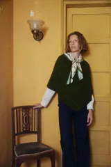 Poncho tejido de punto en color verde oscuro, con diseño de cuello en V y textura acanalada. Presenta una caída holgada y cómoda.
