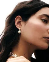Aros en forma de gota de plata con perla de río engarzada en el centro.