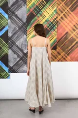 Vestido amplio de lino y algodón, con escote recto y tiras finas. Su corte evasé y los recortes de tela generan una silueta con mucho volumen y movimiento. Estampado de líneas a cuadros en tonos grises y blancos.