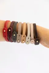 Pulsera de cuero vacuno color borgoña con broche dorado, pulsera de cuero vacuno color rosa pálido, pulsera de cuero vacuno color gris con la palabra "Guiller" grabada y pulsera de cuero vacuno color verde oscuro con la palabra "Enzo" grabada.