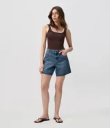 Short midi de jeans de corte recto, con tiro medio, trabillas en la cintura y cierre frontal con botón y cremallera. Cuenta con bolsillos delanteros y posteriores, además de aplicación de tachas metálicas en los laterales.