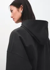 Hoodie de corte oversize color gris oscuro, con capucha ajustable, bolsillo estilo canguro en el frente, mangas largas y puños y ruedo elásticos acanalados.