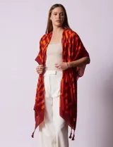Kimono ligero de poliéster con estampado geométrico en tonos rojo oscuro y naranja. Presenta mangas anchas y terminación con borlas en los ruedos.