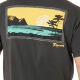 Remera de manga corta color negro con estampado pequeño en el pecho que incluye palmeras y el logo de la marca Rip Curl.