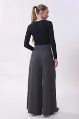 Pantalón de vestir de corte sastrero y pierna ancha (wide leg), confeccionado en tejido de lana gris. Presenta cintura alta con doble botón y pinzas frontales que aportan volumen y caída fluida.