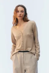 Cardigan de punto fino color beige, con escote en V, cierre frontal de botones y mangas largas.