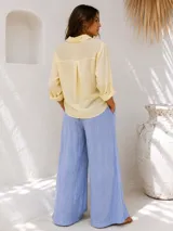 Pantalón palazzo de lino color beige, de corte ancho y tiro alto, con bolsillos laterales y presillas para cinturón.