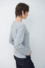 Remera de manga larga con cuello redondo, confeccionada en tejido de punto gris melange con costuras visibles en contraste.
