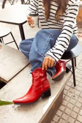 Bota texana corta de cuero color rojo, con punta fina, caña baja y taco cuadrado.