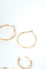 Set de tres pares de aros tipo argolla dorados, de diferentes tamaños y diseños: un par grande de aro fino liso, un par mediano de aro más ancho y liso, y un par pequeño con textura retorcida.