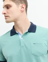Remera manga corta color verde con cuello polo y bolsillo en el pecho. El cuello y los puños son de color azul marino.