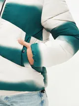 Campera puffer corta con cuello alto, cierre frontal con cremallera y bolsillos laterales. Diseño con bloques de color blanco y verde degradado.