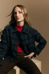 Tapado corto de lana con diseño a cuadros en tonos azul y negro, cuello camisero y cierre frontal con botones.
