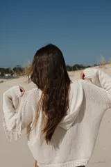 Buzo con capucha de tejido de punto abierto, color blanco roto, de corte oversize y manga larga con detalle de flecos en los puños.