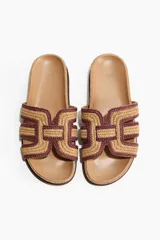 Sandalias H&M tipo chinela con plantilla preformada color tostado y tira ancha en el empeine confeccionada en paja trenzada con diseño geométrico en tonos beige y bordó.