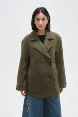 Chaqueta de paño color verde oliva, con cuello solapa, cierre frontal con botones y bolsillos laterales. De corte holgado y manga larga.