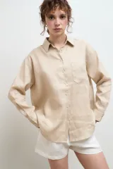Camisa oversize de lino, color tostado, con cuello clásico, cierre frontal de botones y bolsillo en el pecho.