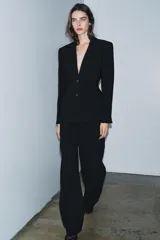 Blazer entallada de Zara Woman Collection, color negro, con cuello solapa de muescas, manga larga con botones en puños y cierre frontal con botones. Presenta bolsillos de vivo en el delantero y detalle de pespuntes marcados a tono.