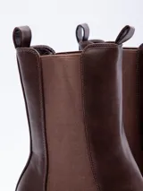 Bota tipo Chelsea de caña alta, confeccionada en cuero sintético negro, con paneles elásticos laterales y suela track con plataforma.