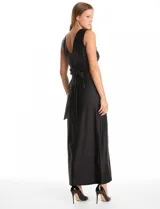 Vestido largo de seda fría color negro, con escote en V profundo, sin mangas y cintura ajustada con banda ancha. Presenta frunces bajo el busto, cierre invisible en la espalda y falda fluida con un tajo lateral pronunciado.