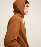 Campera rompevientos color verde oliva con capucha ajustable con cordón, cierre frontal con cremallera, bolsillos laterales con cremallera, puños con elástico y forro interior. Ligera y versátil, ideal para proteger del viento y la lluvia ligera.