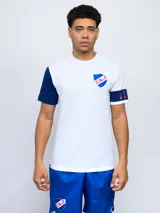 Remera de fútbol blanca con manga derecha azul marino y manga izquierda blanca con una banda azul marino y detalles rojos. Tiene el escudo del Club Nacional de Football en el pecho.