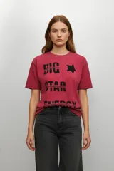 Remera de algodón color rojo gastado con cuello redondo y mangas cortas. Presenta un estampado frontal en color negro con la frase 'BIG STAR ENERGY' y una estrella, con efecto de textura desgastada.