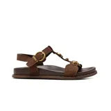 Sandalias planas de gamuza color marrón, con tiras anchas, hebilla metálica dorada de ajuste y detalles de apliques circulares dorados en el empeine.