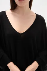 Poncho negro de tejido de punto con escote en V, diseño asimétrico y corte holgado.