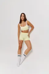 Conjunto deportivo de dos piezas color amarillo limón, compuesto por un top con breteles finos y bordes blancos, y un short ajustado de tiro medio.