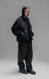 Campera estilo bomber unisex, confeccionada en una combinación de corderito sintético y paneles de ripstop. Presenta un diseño utilitario con múltiples bolsillos frontales con cierres y broches a presión, cuello, puños y ruedo en ribb elástico.