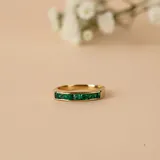 Anillo de oro amarillo 18k con diseño de media alianza engastada con esmeraldas en talla brillante.
