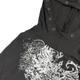 Remera de manga larga con capucha integrada, color negro con estampado gráfico frontal en blanco. La capucha presenta detalles de ojales metálicos decorativos.