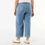 Pantalón jean de tiro alto y pierna ancha, de color azul medio con lavado suave. Presenta bolsillos de parche delanteros, costuras decorativas y un delicado bordado floral blanco en el ruedo.