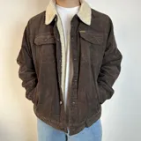 Chaqueta de pana color beige con forro de corderito en el cuello y el interior. Tiene cierre con botones, bolsillos en el pecho y bolsillos laterales.