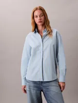 Camisa de corte clásico con estampado de rayas verticales en tonos celeste y amarillo. Presenta cuello en punta, mangas largas con hombros caídos y cierre frontal mediante botones.