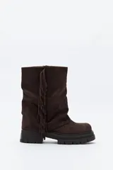 Bota de caña media con flecos laterales, confeccionada en material con textura tipo gamuza. Presenta una silueta relajada y una suela robusta con base dentada.