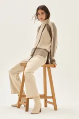 Polera de cuello alto confeccionada en lana lambswool, con diseño de bloques de color en tonos beige y marrón. Presenta mangas raglán con textura acanalada y detalles en hilo metalizado lurex.